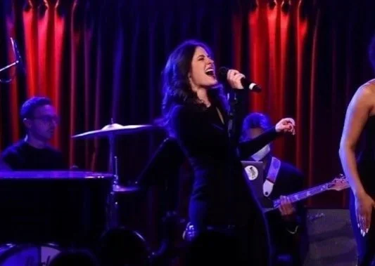 Emily singing with a band on stage