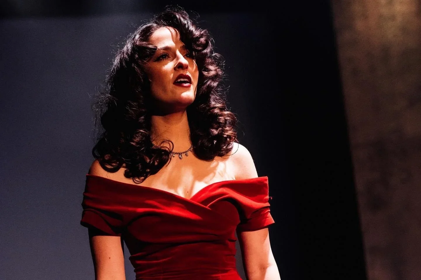 Emily in an elegant off-the-shoulder red dress on stage